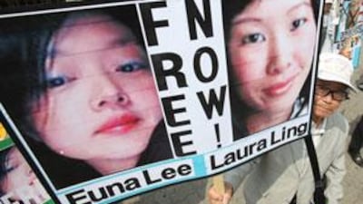 A South Korean protester displays portraits of American journalists detained in North Korea as they shout slogans during a rally in Seoul.