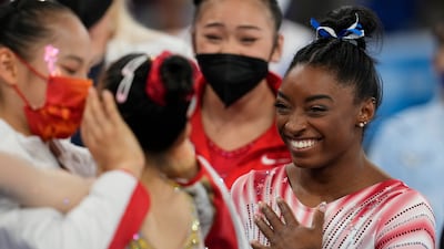 Simone Biles, of the United States, smiles as Tang Xijing, of China, left, embraces teammate Guan Chenchen after the latter won the gold medal on the balance beam during the artistic gymnastics women's apparatus final at the 2020 Summer Olympics.