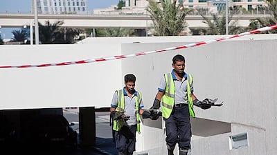 Workers start to clear debris from Tamweel Tower. Antonie Robertson / The National