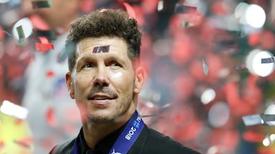 Atletico's head coach Diego Simeone is seen through flying confetti. AP