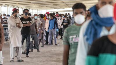 Men wait in line to have their temperature taken at one of two testing centres set up in Mussaffah, Abu Dhabi. Antonie Roberston / The National
