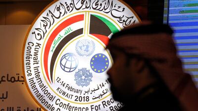 A Kuwaiti official stands in front of an illuminated sign for a conference on Iraq being held in Kuwait City. Jon Gambrell / AP