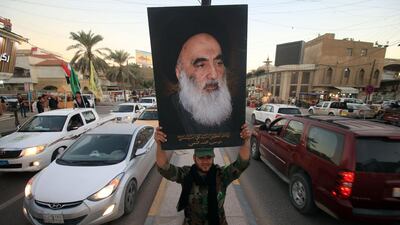 A member of the Hashed al-Shaabi carries a portrait of Iraqi Shiite cleric Grand Ayatollah Ali Al Sistani in a street in the southern city of Basra. AFP