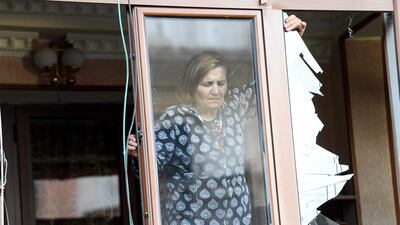 A woman removes broken glass from a window in an apartment building that was damaged by recent shelling in the breakaway Nagorno-Karabakh region's main city of Stepanakert. AFP
