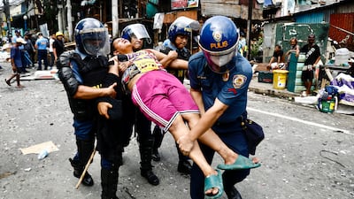 Riot police carry an injured Filipino settler during a demolition raid at a shanty town in Pasay City, Metro Manila, Philippines. EPA