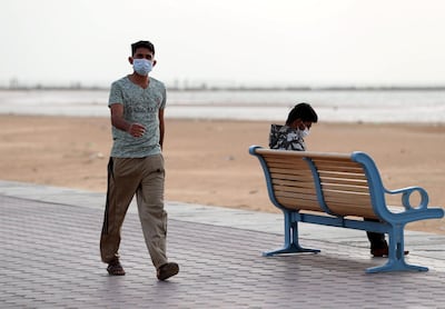 Residents wear face masks on a beach in Ajman. Chris Whiteoak / The National