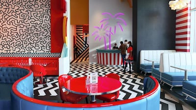 The interiors feature shades of bright red and Tiffany blue, plenty of chrome elements, plush booths and black and white floors.