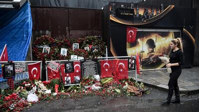 A woman lays flowers by a makeshift memorial in front of the Reina nightclub in Istanbul on January 17, 2017, a day after Turkish police arrested the suspected attacker. The club has since been demolished. Ozan Kose / AFP