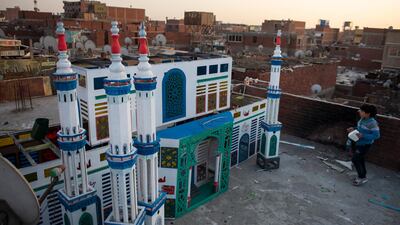 A child walks by a wooden mosque set up as Ramadan decoration to welcome the holy month in Egypt's capital city Cairo. Muslims in large parts of the world start the month of fasting on Tuesday. EPA