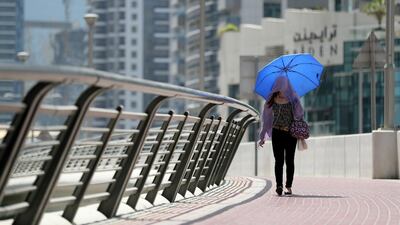 A women protects herself from the sun on a hot day in Dubai. Chris Whiteoak / The National