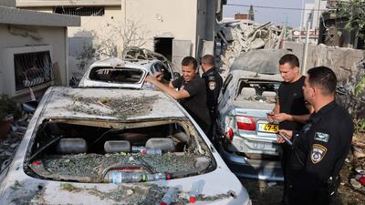 Police officers and residents view damaged cars in Tira, central Israel after the rocket attack. AFP