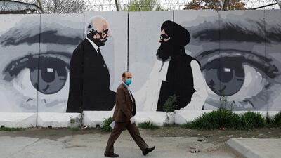 An Afghan man wearing a protective face mask walks past a wall painted with photo of Zalmay Khalilzad, US envoy for peace in Afghanistan. Reuters