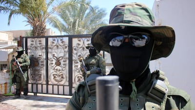 Iraqi fighters of the Shiite group Asaib Ahl Al Haq (The League of the Righteous) stand guard outside their headquarters on May 18, 2015, in the mainly Shiite southern city of Basra, as Shiite militias converged on Ramadi in a bid to recapture it from ISIS.