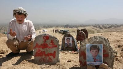 An Afghan man prays in front of the graves of victims of a suicide attack in Kabul on July 25, 2016. Rahmat Gul/AP Photos