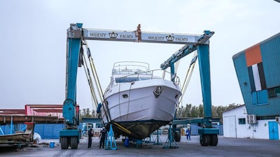 The maintenance yard area. Workers remove barnacles from a hull before painting the boat.