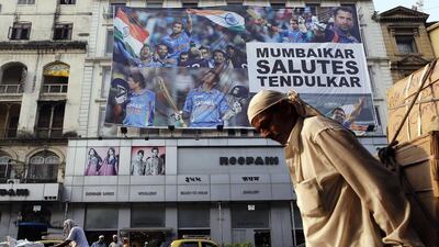 A porter pulls a handcart past a billboard of cricketer Sachin Tendulkar in Mumbai on Friday. Tendulkar fell short of a fairytale ton in his farewell test, but the Indian batsman's 74-run knock was embellished by a full repertoire of classy shots the 'Little Master' was renowned for during a sparkling 24-year career. Danish Siddiqui / Reuters