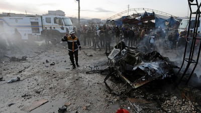People stand near a burnt car at the site of a truck blast in Azaz, Syria. REUTERS