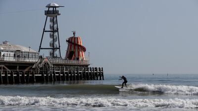 A surfer rides a wave in front of the pier at Bournemouth beach. Reuters
