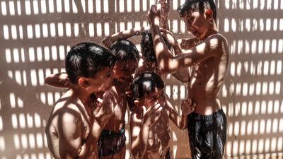 Palestinian children use a shower to cool off on a hot summer day in Gaza City. AFP