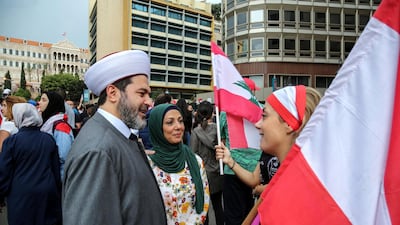 A Sunni cleric chat with a protester carrying Lebanese flags at the seventh day of protest in Beirut, Lebanon. EPA