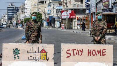 Mask-clad policemen loyal to Hamas stand behind concrete barriers painted with messages instructing people to remain at home at a checkpoint in Rafah in the southern Gaza Strip. AFP