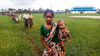 A woman holds a child in her arms as she arrives at the Yathae Taung township in Rakhine State in Myanmar with other terrified refugees fleeing from violence in their village on August 26, 2017. Wai Moe/AFP