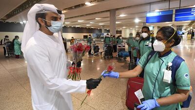 An Emirati official presents a rose to an Indian nurse, part of an 80 person medical team, upon her arrival at Dubai International Airport, May 12. AFP