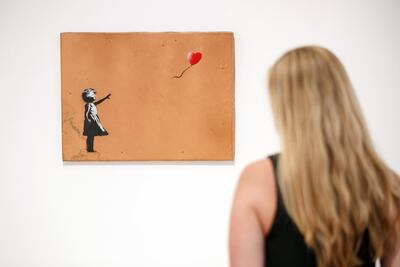 A visitor at the Lazinc Gallery in London looks at Banksy's 'Girl with Balloon' (2006). The signed print version of the artwork is included in Sotheby's first online auction dedicated to the street art. AFP