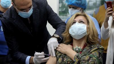 Lebanon's caretaker health minister, Hamad Hasan, administers a dose of the Pfizer/BioNTech vaccine to a woman in Beirut last month. Reuters