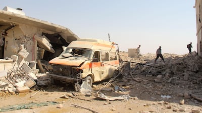 People walking through rubble and debris past a damaged ambulance following a reported air strike by Syrian government forces in the village of Al Tahh, in the north-western Idlib province on September 19, 2017. Omar Haj Kadour / AFP