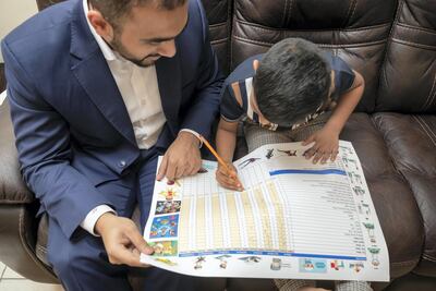Zayyan Furquan, aged six, along with his farther Nas mark off the points he’s accumulated for all the chores and homework he has completed. Antonie Robertson/The National