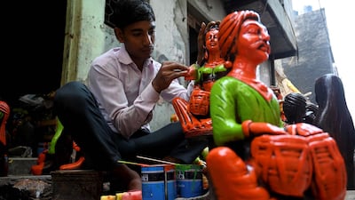 In this photograph taken on October 4, 2019, a boy colours a decorative item made of clay outside his residence at Kumhar Gram (Potter's Village) in New Delhi. The narrow lanes of Kumhar Gram are buzzing with activity ahead of Diwali as generations of potters race to create clay decorations for customers across the country - and beyond. Known as the "Potter's Village", the settlement is home to around 500 families from India's traditional pottery community, who moved to the area half a century ago. Photo: AFP