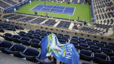 Spectators take cover during a rain delay on Wednesday at the US Open in one of the women's quarter-final matches. David Goldman / AP