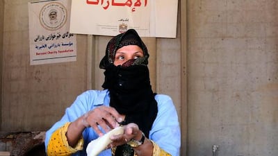 A displaced Iraqi woman, who fled conflict between government forces and ISIL terrorists, prepares to bake bread following food aid distributions by the Emirates Red Crescent. Safin Hamed / AFP
