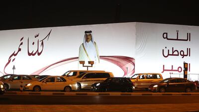 In this file photo taken on June 11, 2017 A general view taken on June 11, 2017 shows a portrait of Qatar's Emir Sheikh Tamim bin Hamad Al-Thani and text reading in Arabic: "We are all Tamim" on a billboard outside the Qatar Sports club in Doha. AFP / Karim JAAFAR