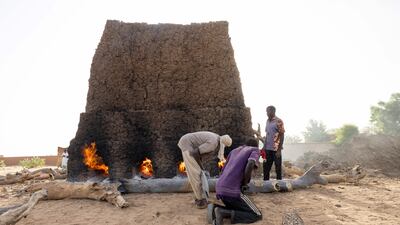 Refugees push logs into a brick oven in Adre