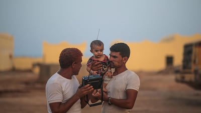 Refugees listen to the news on the radio outside their room at an orphanage that has been turned into a center for Yemeni refugees.