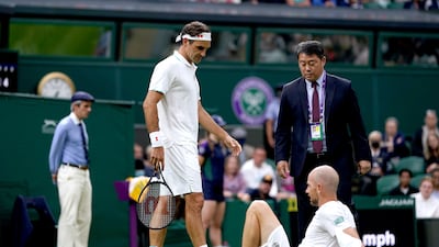 Roger Federer speaks to Adrian Mannarino after he slipped on the grass and picked up a match-ending injury. PA