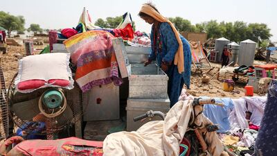 A woman goes through her belongings next to the ruins of her house after heavy monsoon rains in Rajanpur district, Punjab province. AFP