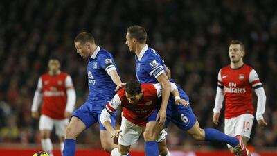 Arsenal's Mesut Ozil, centre, stumbles as he is fouled by Everton's James McCarthy, left, and Phil Jagielk during a Premier League game yesterday. AP Photo / Kirsty Wigglesworth