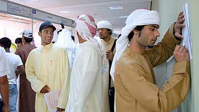 Emirati students looking for a job in the private sector fill up forms during a career fair held at Men's Dubai College.