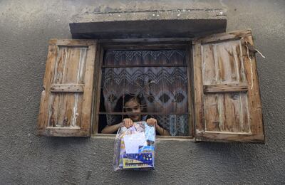 A girl displays a package of crafts and reading material distributed by volunteers during a lockdown in the Deir Al Balah refugee camp, Gaza Strip, in April. AFP