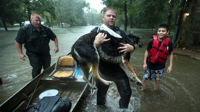 Splendora Police officer Mike Jones carries Ramiro Lopez Jr.'s dog, Panthea, from a boat after the officers rescued the family from their flooded neighborhood as rains from Tropical Depression Imelda inundated the area, Thursday, Sept. 19, 2019, in Splendora, Texas. AP
