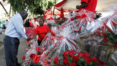 A Kenyan woman sells a bouquet of red roses to a customer for celebrations of Valentine's Day at a flower market in Nairobi, Kenya, Tuesday, Feb. 14, 2012. (AP Photo/Sayyid Azim)