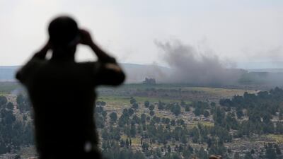 A Turkey-backed Free Syrian Army soldier watches with binoculars as smoke rises after a bomb attack during an offensive, at Der Mismis Village, southeast of Afrin, EPA