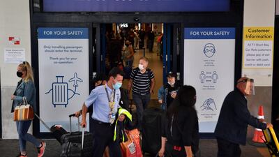 Passengers wearing a face mask or covering due to the Covid-19 pandemic, react as they exit Terminal 1 after landing at Manchester Airport in Manchester, north west England on July 27, 2020 AFP