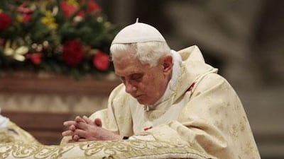 Pope Benedict XVI kneels in prayer during Christmas Mass in St Peter's Basilica at the Vatican yesterday.