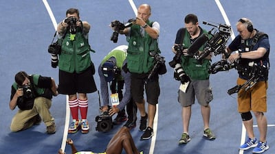 Photographers take photos of Jamaica’s Elaine Thompson (bottom) after she won the women’s 100m final during the athletics event at the Rio 2016 Olympic Games at the Olympic Stadium in Rio de Janeiro on August 13, 2016. John MacDougall / AFP
