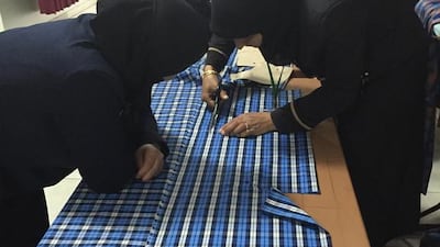 Syrian widows cutting patterns to make shorts for boys.