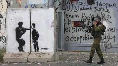An Israeli soldier walks past a section of Israel's controversial barrier during clashes with Palestinian protesters following a rally ahead of Nakba day in the West Bank city of Bethlehem. Ammar Awad / Reuters